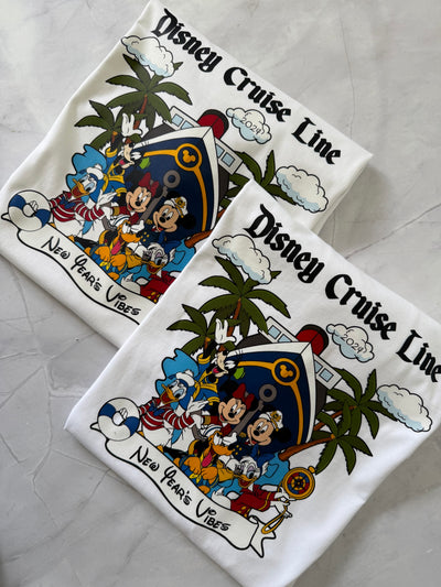 Two Disney Cruise Line shirts with characters and palm trees on a gray surface