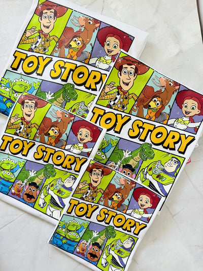 Flat lay of The Toy Box Crew family t-shirts featuring Toy Story-inspired design and playful colors.