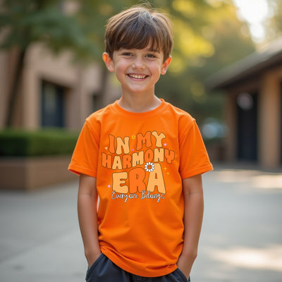 Child wearing an orange t-shirt with text in my harmony era outdoors