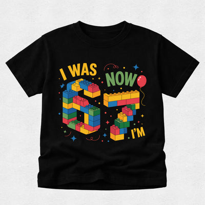 Black t-shirt with colorful birthday design on a light gray background