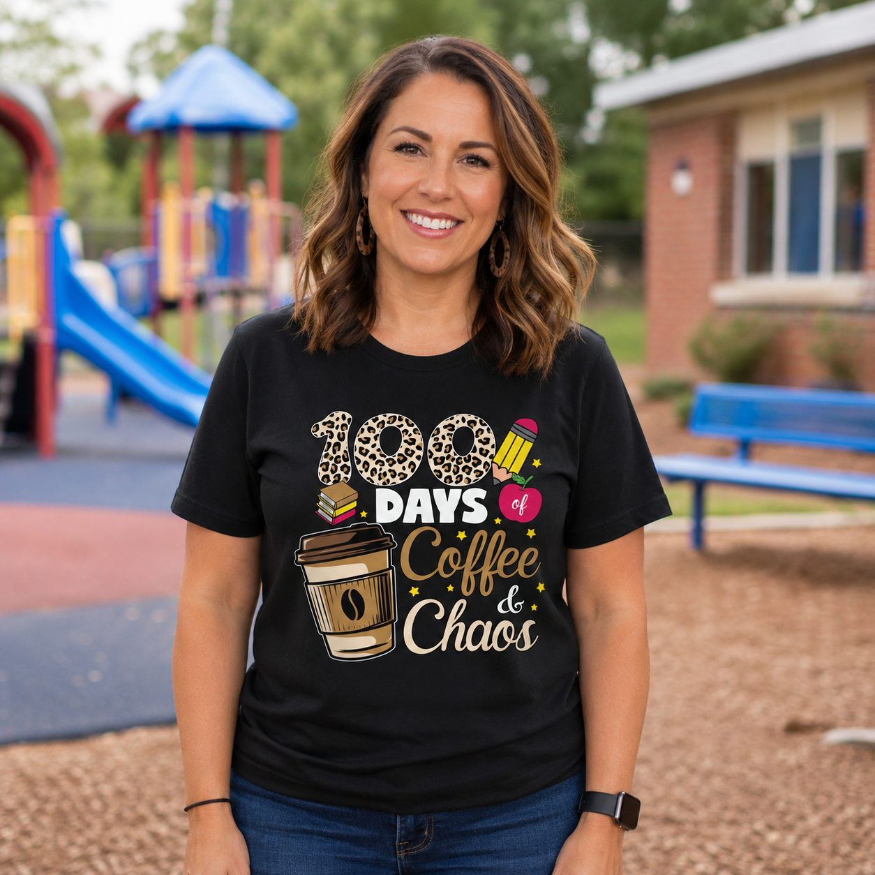 A woman wearing a black graphic t-shirt with a '100 Days Coffee & Chaos' print, standing in a blurred outdoor playground setting.