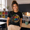 Woman wearing a black t-shirt with a colorful '100 Days of School' design in a classroom setting.