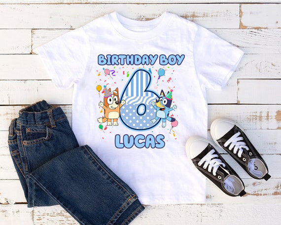 White t-shirt with 'Birthday Boy 6 Lucas' design, paired with jeans and black sneakers on a wooden surface.