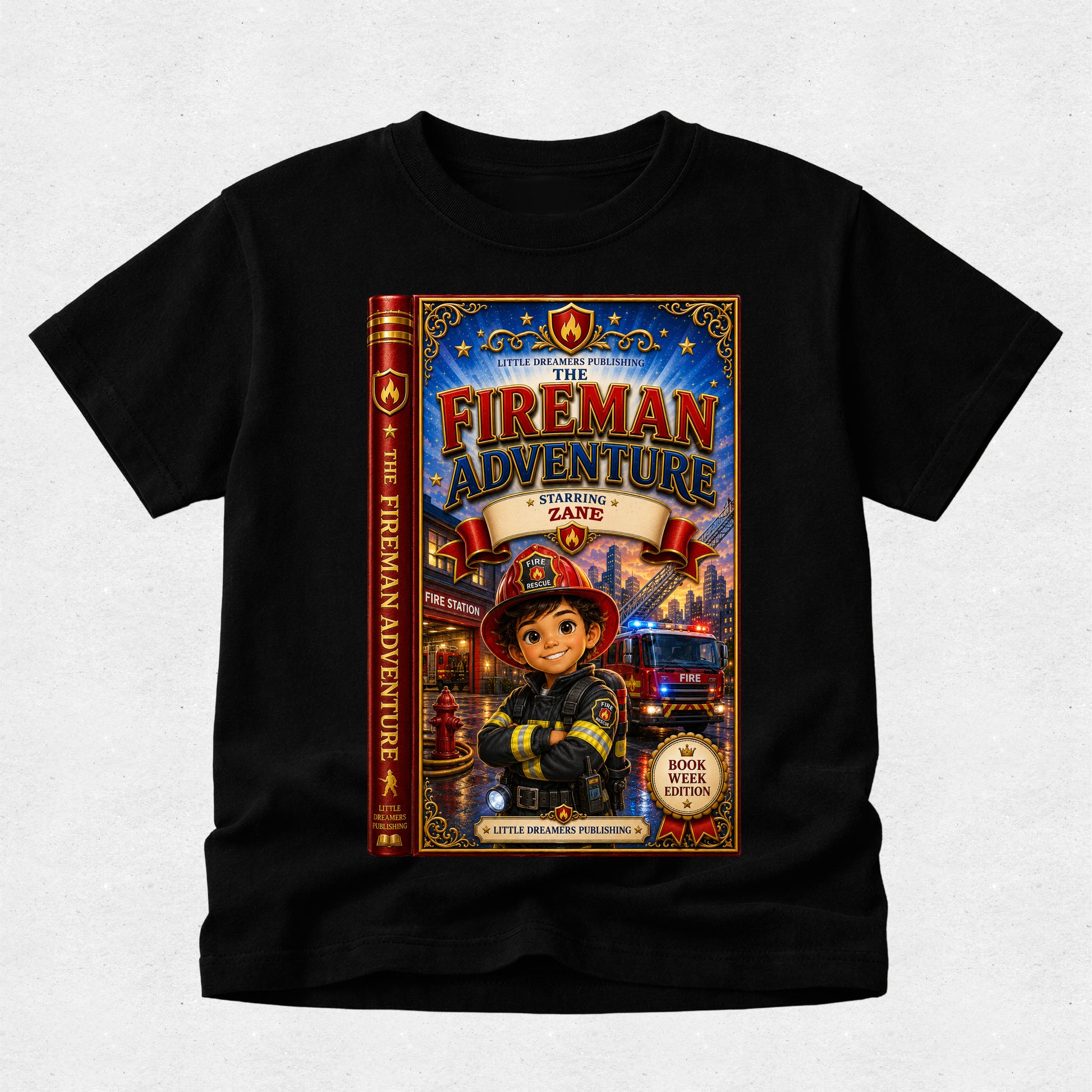 A black short-sleeve t-shirt with a large, colorful graphic print on the front depicting the book cover of 'The Fireman Adventure: Learning Zane'. The shirt is displayed flat against a light gray textured background.