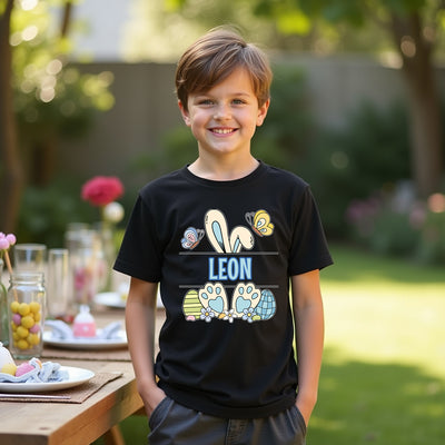Child wearing a black t-shirt with colorful graphics and the name 'Leon' outdoors.