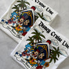 Two Disney Cruise Line shirts with characters and palm trees on a gray surface