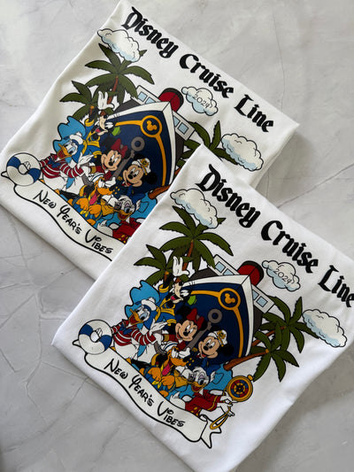 Two Disney Cruise Line shirts with characters and palm trees on a gray surface