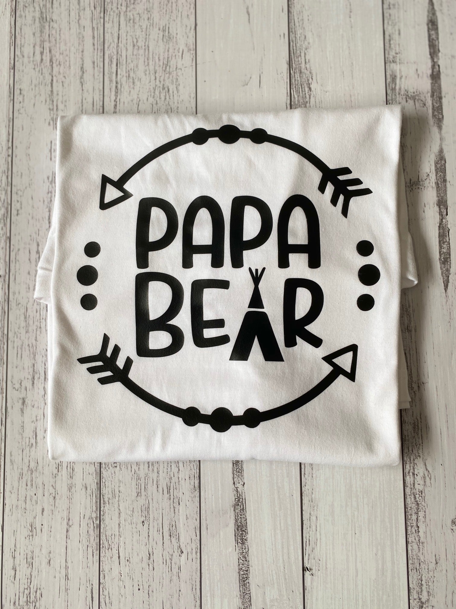 White t-shirt with 'Papa Bear' text on a wooden surface