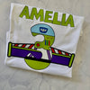 White t-shirt with a colorful design and 'Amelia' text on a textured surface