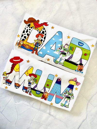 Two tshirts with toy story cartoon characters and colorful text on a textured white surface.