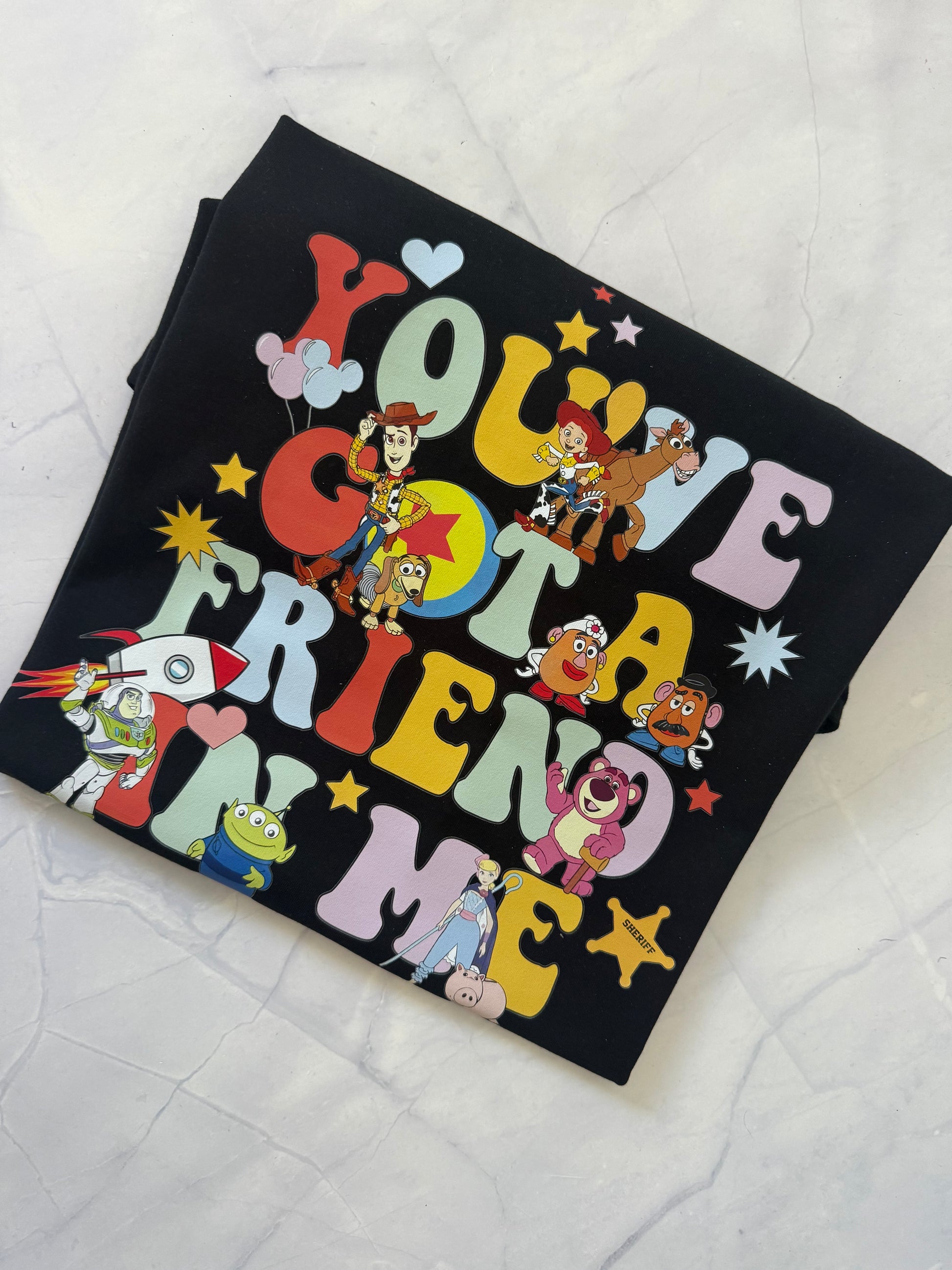 Black t-shirt with colorful cartoon character design on a white surface