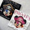 Two pirate-themed t-shirts with cartoon characters Mickey and MInnie on a textured surface