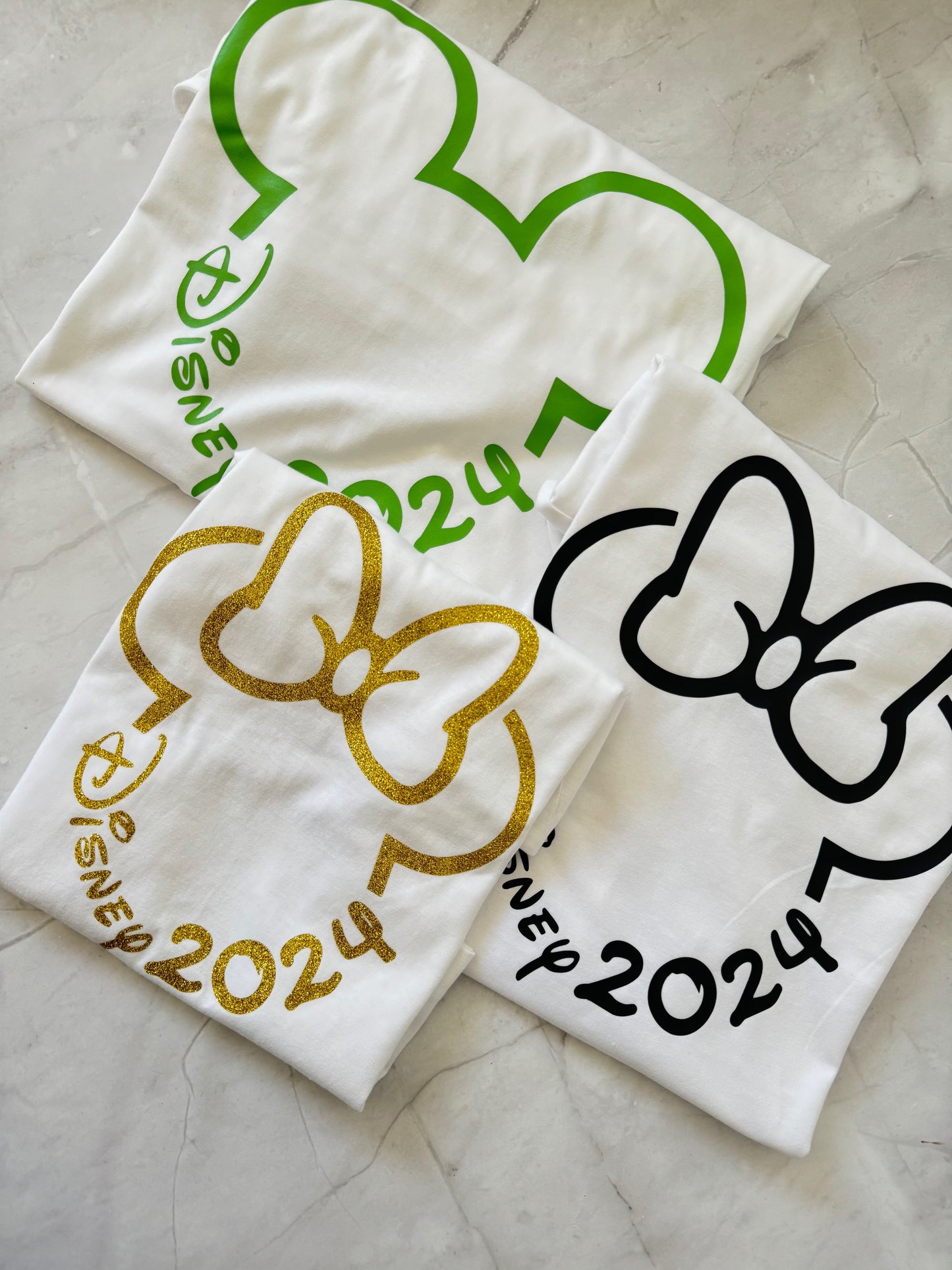 Three white t-shirts with Disney-themed designs 