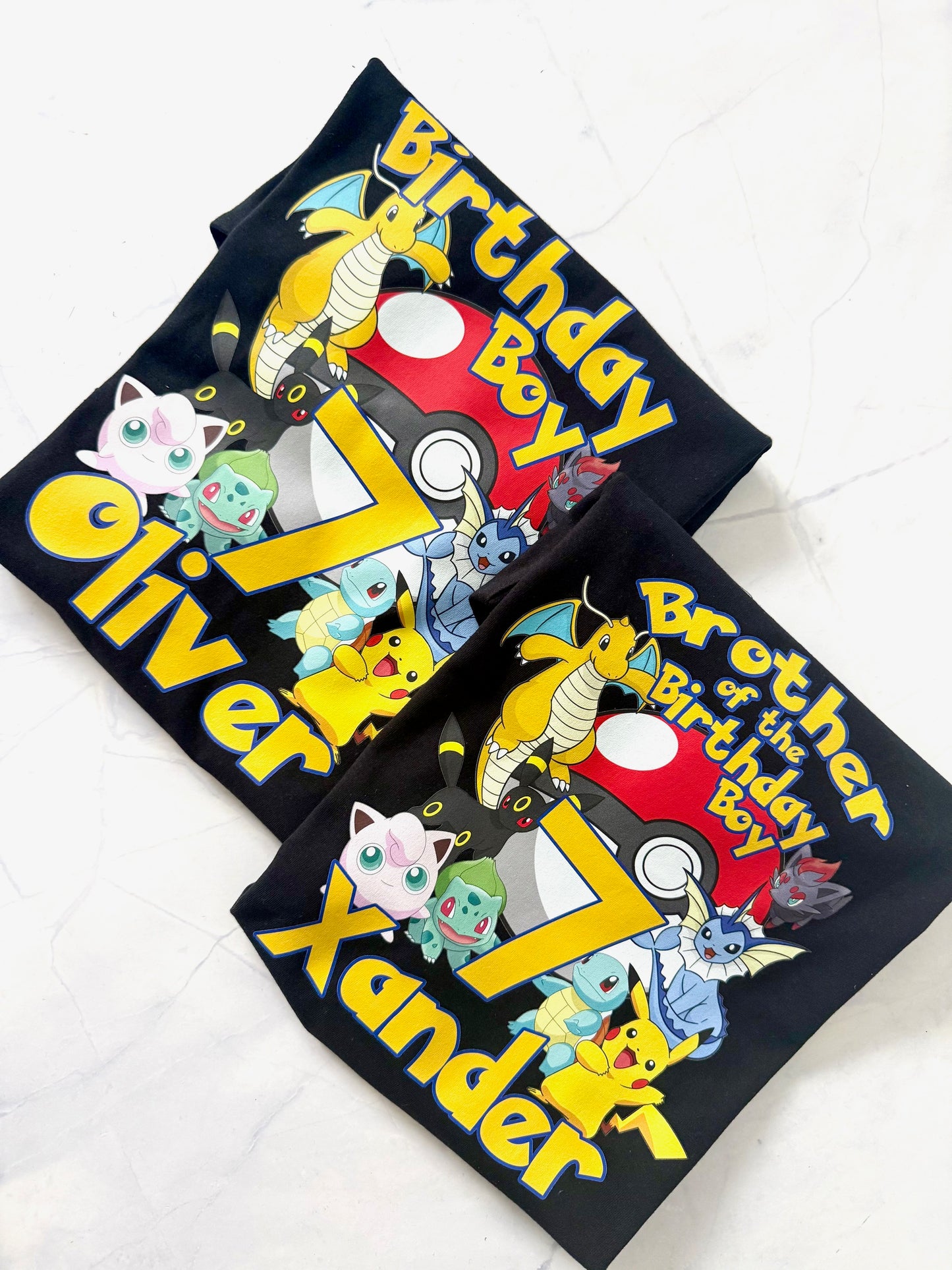 Two black t-shirts with colorful graphics and text on a white background