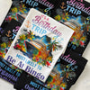 A styled flat-lay of folded graphic T-shirts on a light marble surface. The shirts feature colorful tropical cruise ship illustrations with palm trees, flowers, and anchors, along with humorous birthday-themed text including 'IT'S A Birthday TRIP' and 'MOST LIKELY TO Be At Bingo'.