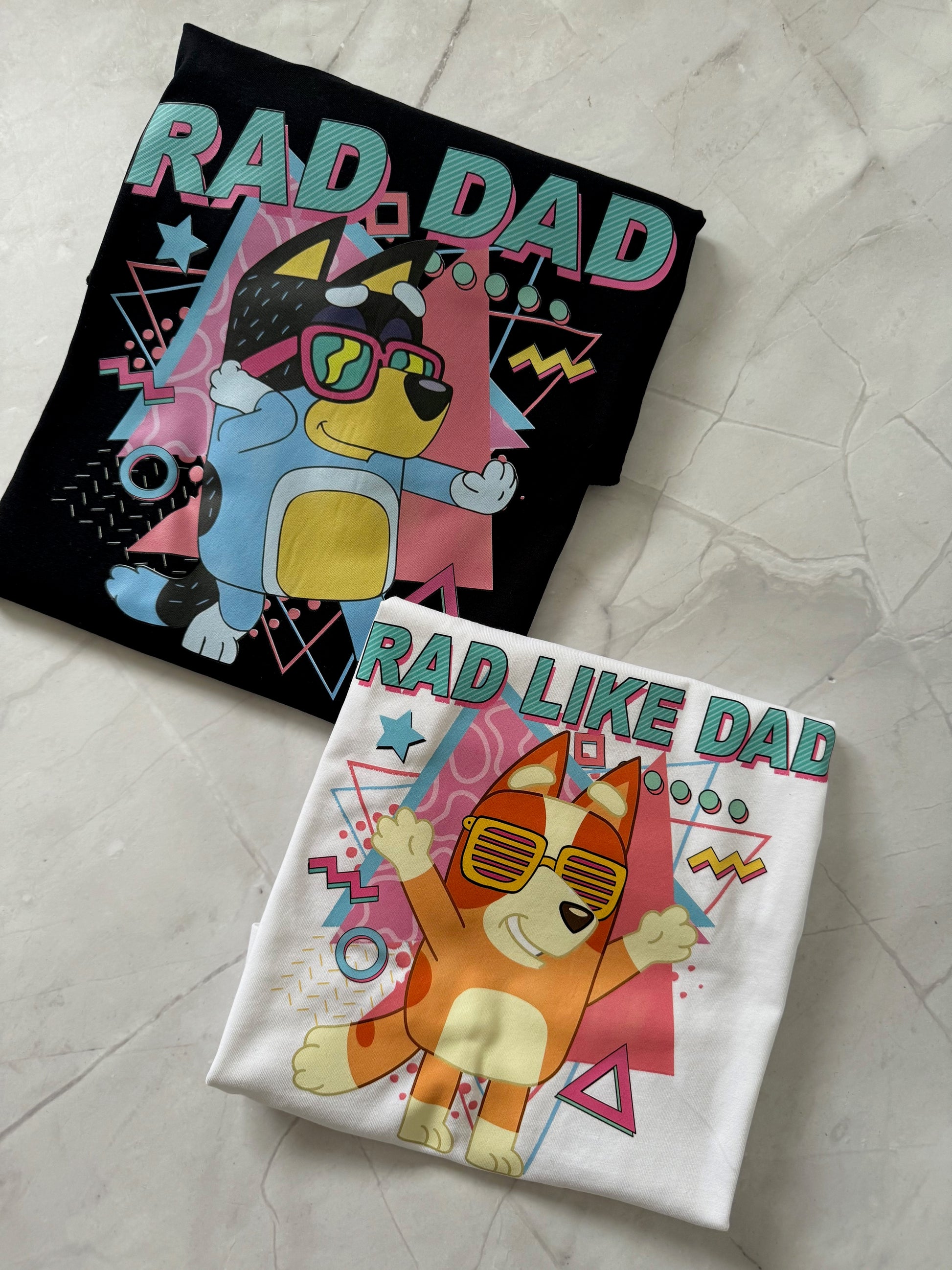 Close-up of Rad Dad Bluey inspired t-shirt design on black and white shirts