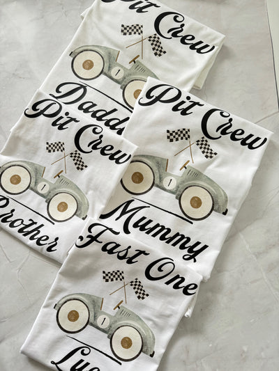 Stack of matching Race Day Pit Crew shirts labeled “Daddy Pit Crew,” “Brother Pit Crew,” and “Fast One.”