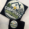 Two folded black T-shirts laid flat on a light textured surface, each printed with a large circular 'Corporate Houses Trivia Team' logo featuring a house, lightbulb, question marks, and bridge graphic.