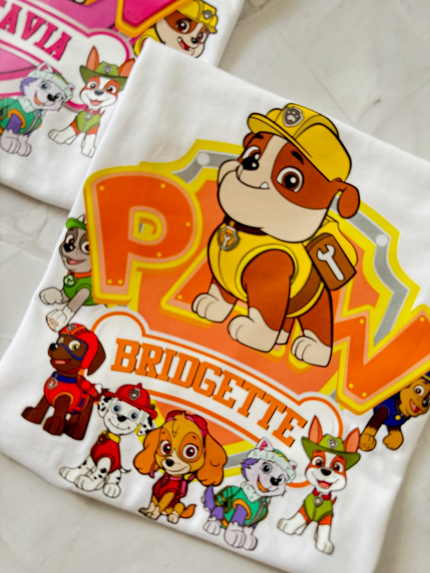 Close-up of Rubble character on birthday shirt with bright yellow "PAW" design and custom name below.