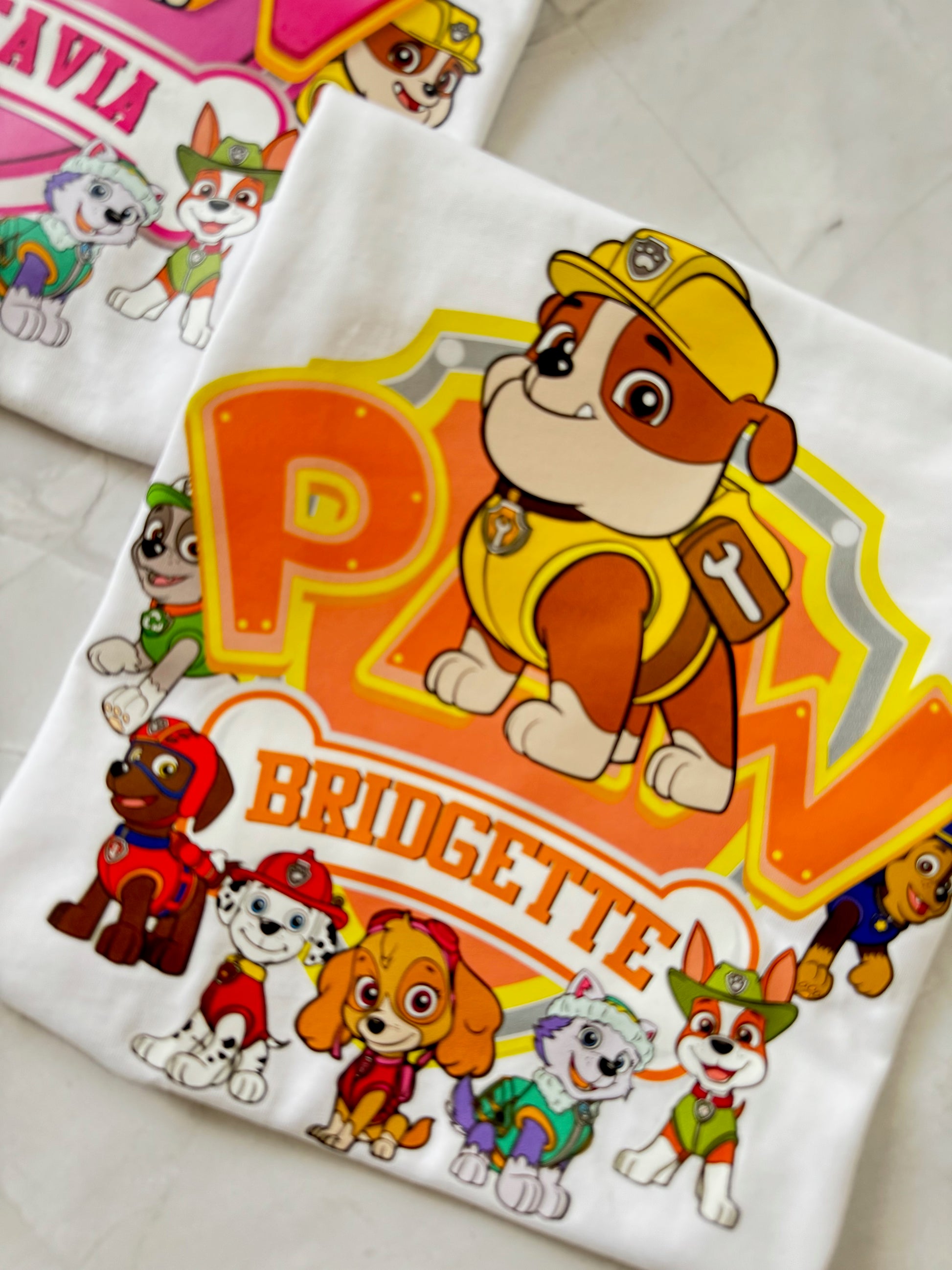 Close-up of Rubble character on birthday shirt with bright yellow "PAW" design and custom name below.