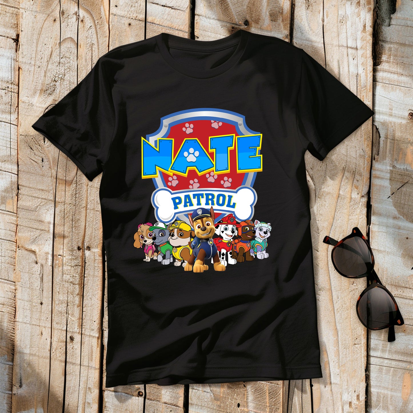 Black t-shirt with 'Nate Patrol' design featuring cartoon characters on a wooden surface.