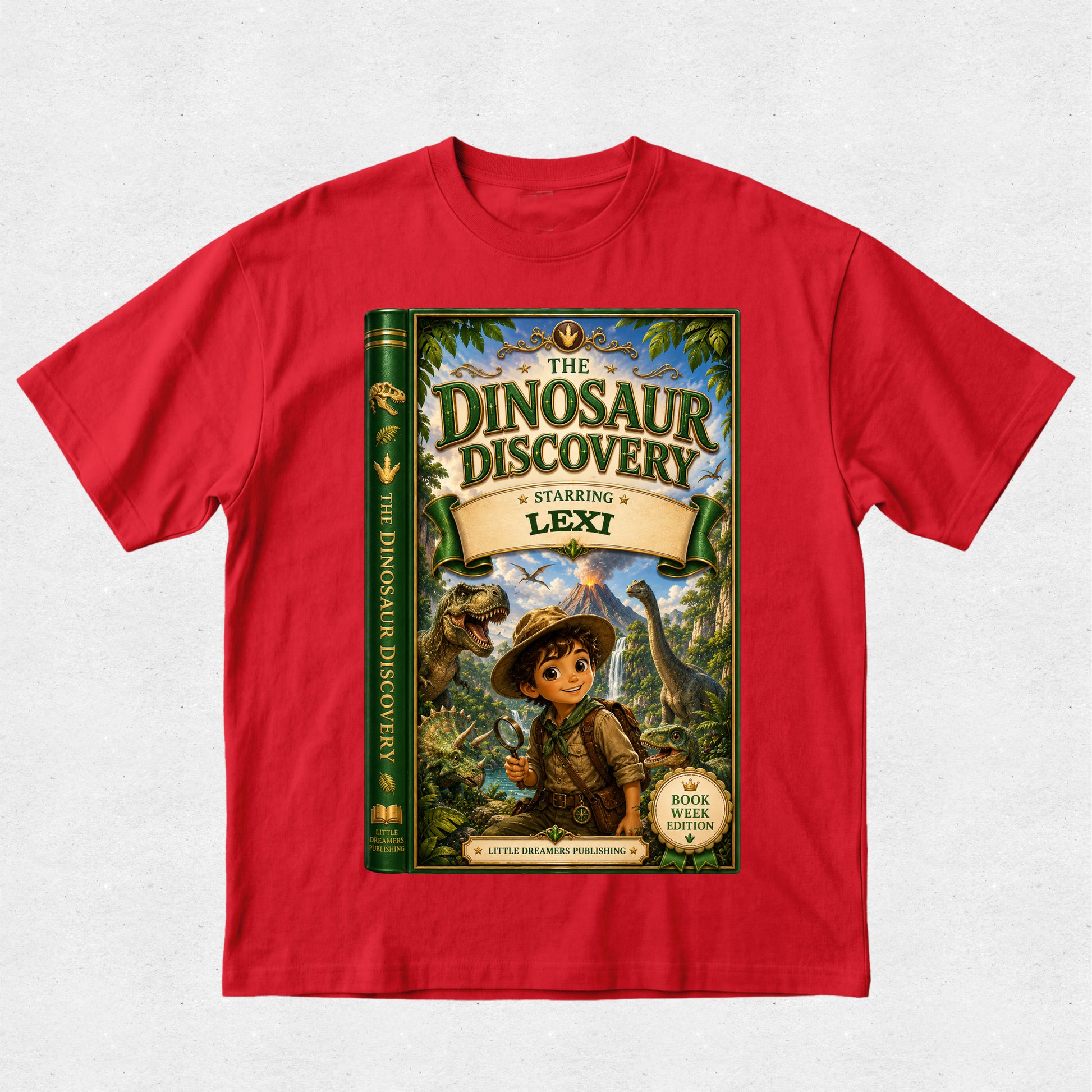 A red short-sleeve crewneck t-shirt featuring a large graphic print of a children's book titled 'The Dinosaur Discovery: Starring Lexi' on the front, displayed flat against a light gray textured background.