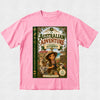 A pink short-sleeve crewneck t-shirt featuring a large graphic print of a book cover titled 'The Australian Adventure Starring Audrey'. The graphic depicts a young girl in a safari hat and vest with a koala and a kangaroo, set against a light gray textured background.