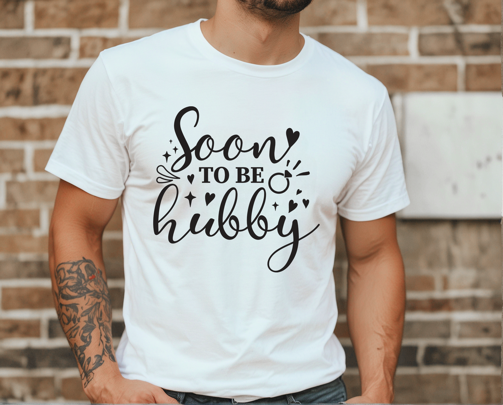 Person wearing a white t-shirt with 'Soon to be hubby' text against a brick wall.