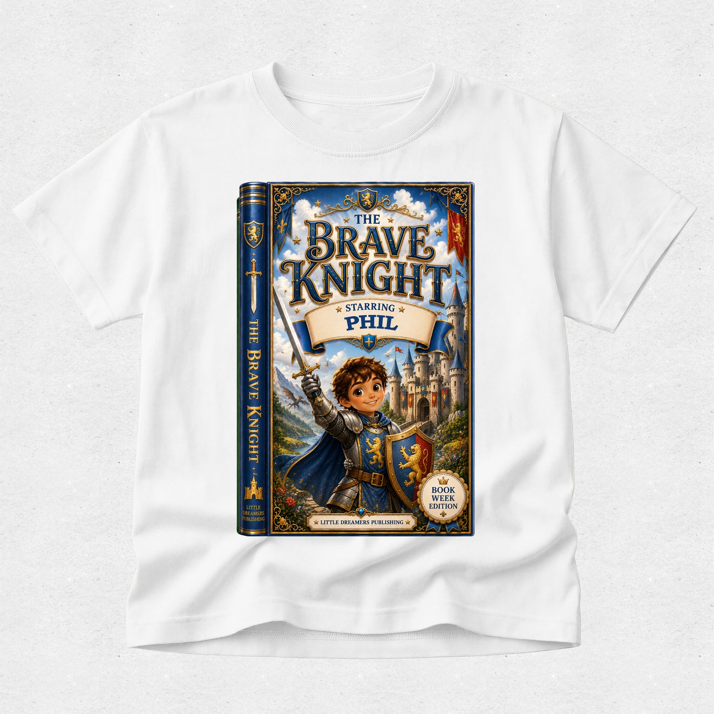 A white kids' t-shirt featuring a large graphic print of the book cover for 'The Brave Knight Starring Phil'. The graphic shows a young boy knight in blue and gold armor holding a sword, standing in front of a castle.
