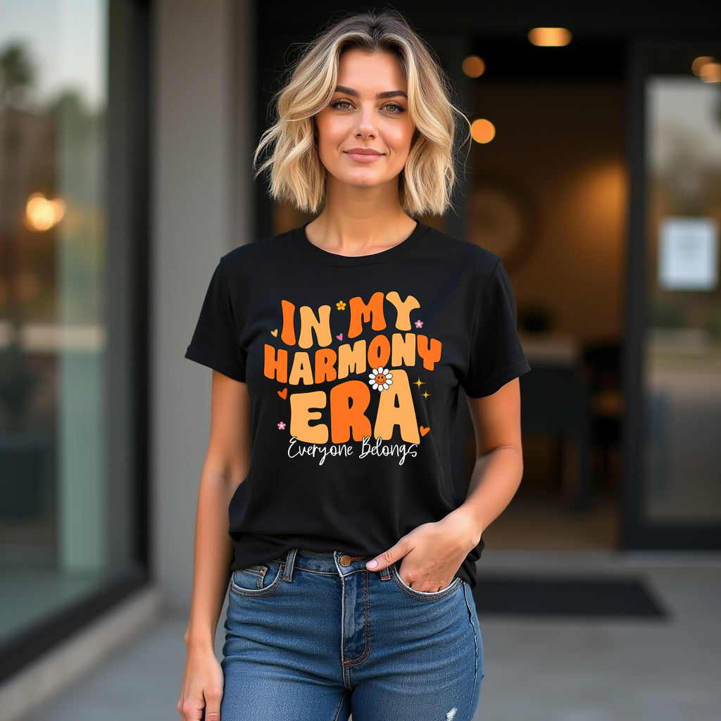 Woman wearing a black t-shirt with orange text in my harmony era standing outdoors.