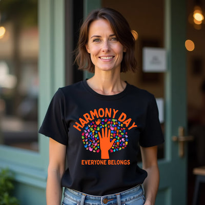 Woman wearing a black t-shirt with 'Harmony Day Everyone Belongs' design, standing outside a building.