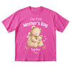 Pink t-shirt with teddy bear design and 'Our First Mother's Day Together 2026' text on a white background