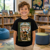 A smiling young boy stands in a children's library wearing a black graphic t-shirt featuring a book cover design titled 'The Australian Adventure' with 'Timmy' printed below it. The background shows bookshelves, a globe, and colorful bean bags.