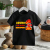 Black t-shirt with a fire truck graphic and text on a hanger in a room setting.