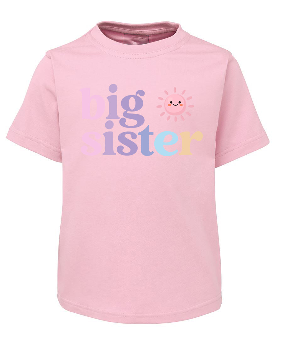 Pink t-shirt with 'big sister' text and sun graphic on a white background
