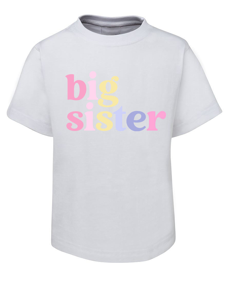 White t-shirt with 'big sister' text in colorful letters on a white background