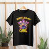 Black t-shirt with 'Birthday Girl' design featuring three girls and a purple triangle on a wooden rack.