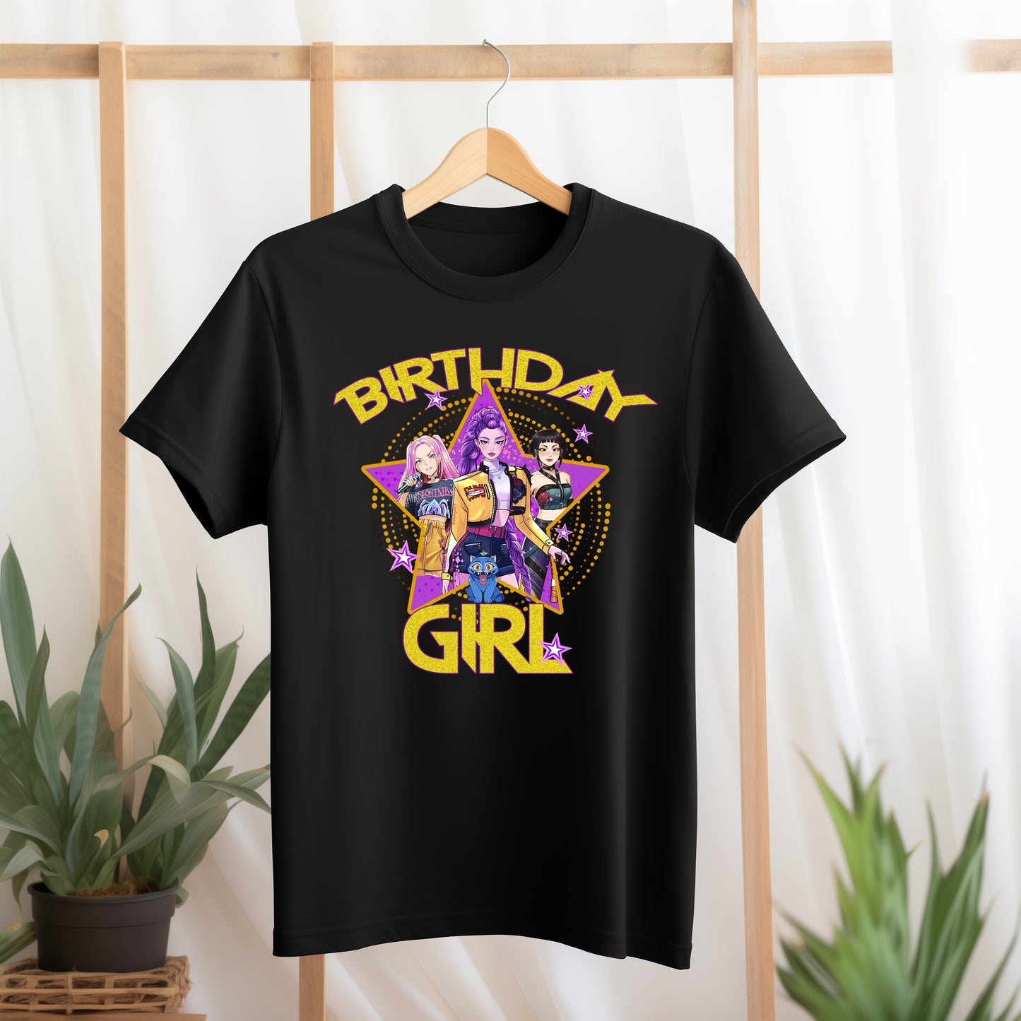 Black t-shirt with 'Birthday Girl' design featuring three girls and a purple triangle on a wooden rack.