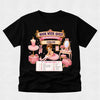 A black short-sleeve t-shirt with a detailed graphic print on the front. The graphic features a pink and gold 'Book Week Quest' banner with 'Ballerina Studio' and 'Chloe' written on it, surrounded by illustrations of a ballerina, a pink tutu, a vanity table, and a pink handbag, with a checklist below reading 'Can You Find?'.