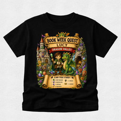 A black short-sleeve t-shirt with a colorful graphic print on the front. The graphic features a cartoon boy holding a sword next to a green dragon, set against a fantasy castle and treasure scene with text reading 'BOOK WEEK QUEST', 'LUCY', and 'DRAGON VALLEY'.