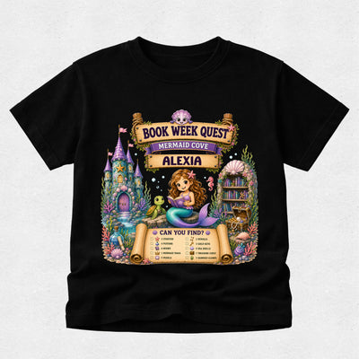A black short-sleeve t-shirt with a colorful graphic print on the front. The graphic features a mermaid, a castle, a library, and scrolls reading 'BOOK WEEK QUEST', 'MERMAID COVE', and 'ALEXIA', along with a checklist at the bottom.