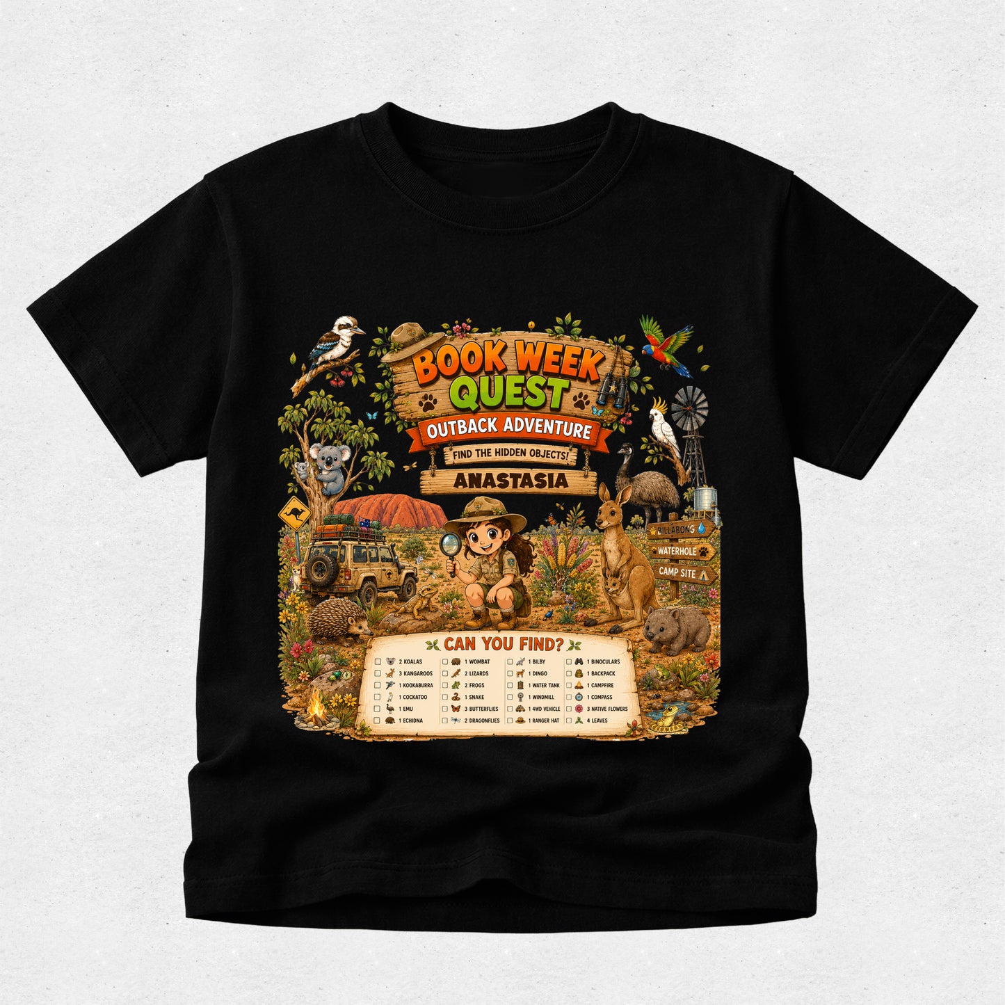 A black short-sleeve crewneck t-shirt featuring a large, colorful graphic print on the front. The graphic is themed around a 'Book Week Quest Outback Adventure' and depicts a cartoon character in a safari hat with a magnifying glass, surrounded by various animals, a windmill, and a checklist titled 'CAN YOU FIND?'.