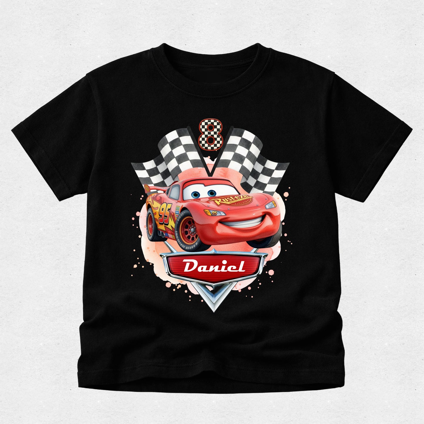 Black t-shirt with a cartoon car design and 'Daniel' on a light gray background