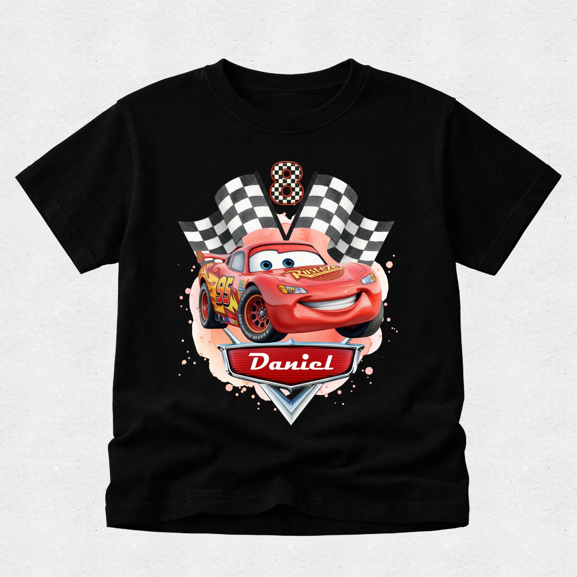 Black t-shirt with a cartoon car design and 'Daniel' on a light gray background