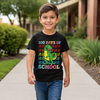 Child wearing a black t-shirt with a colorful dinosaur graphic and text, standing outdoors.