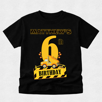 Black t-shirt with a construction-themed birthday design on a light gray background