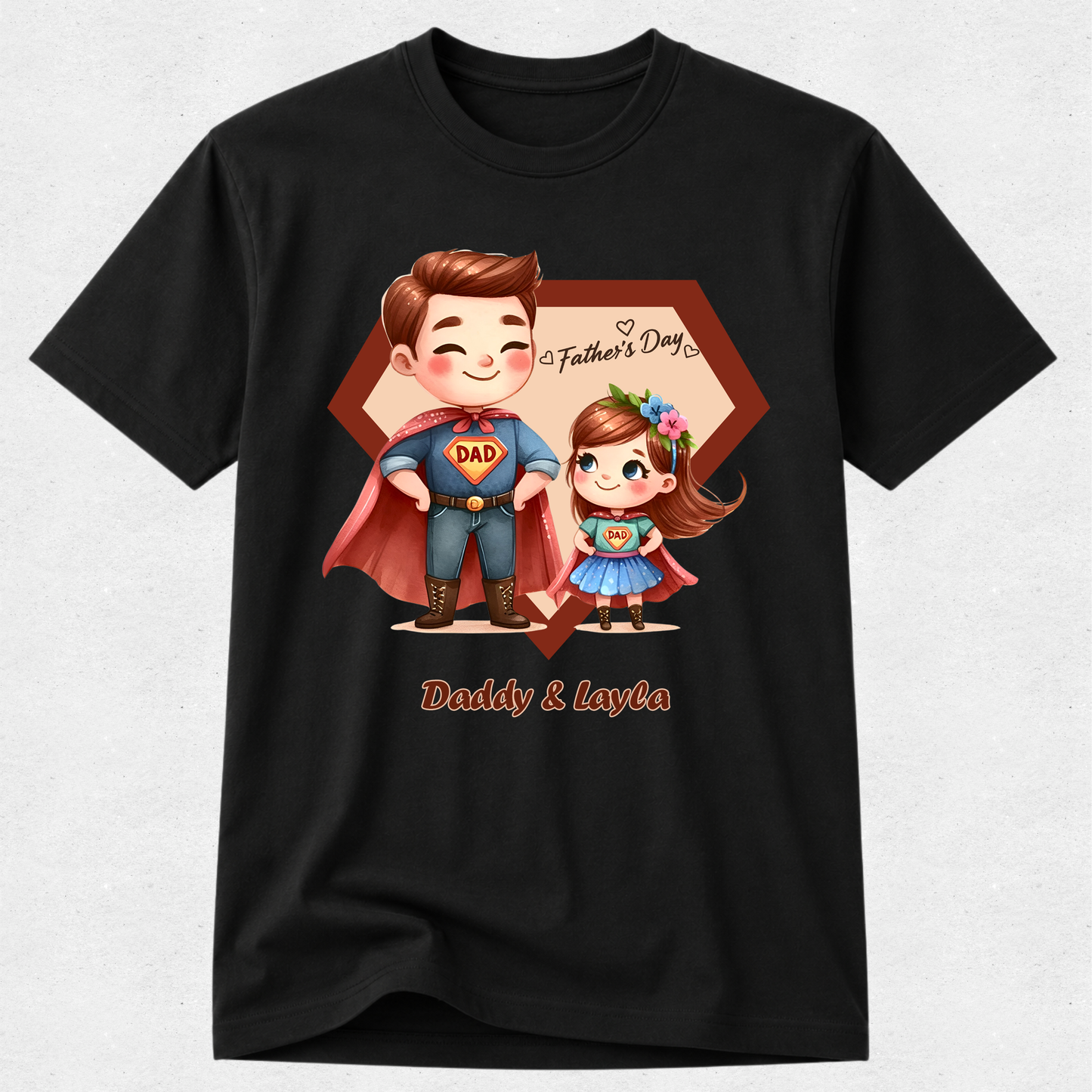 A black short-sleeve crewneck t-shirt with a custom cartoon graphic of a father and daughter dressed as superheroes, with 'Father's Day' and 'Daddy & Layla' text, displayed on a light gray textured background.