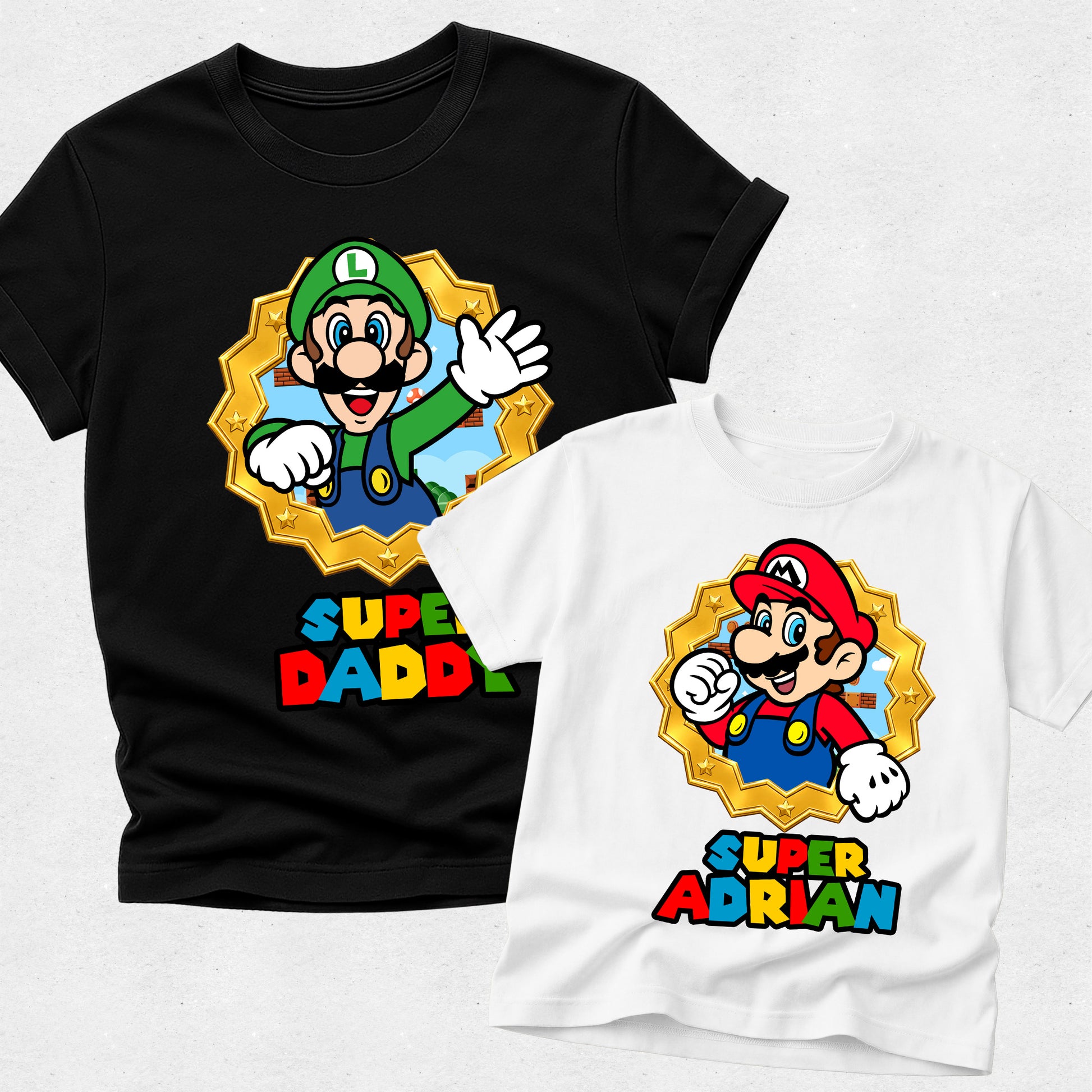 Black t-shirt with Luigi graphic and 'Super Daddi' text, white t-shirt with Mario graphic and 'Super Adrian' text on a light gray background.