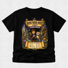 A black short-sleeve crewneck t-shirt featuring a large, colorful graphic print on the front. The graphic is themed around 'Book Week Quest' at the 'Leroy Wizard Academy' and shows an illustration of a young boy wizard holding a wand next to an owl, with scrolls, castles, and magical items in the background.