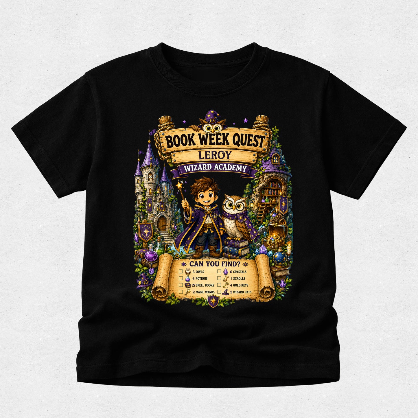 A black short-sleeve crewneck t-shirt featuring a large, colorful graphic print on the front. The graphic is themed around 'Book Week Quest' at the 'Leroy Wizard Academy' and shows an illustration of a young boy wizard holding a wand next to an owl, with scrolls, castles, and magical items in the background.
